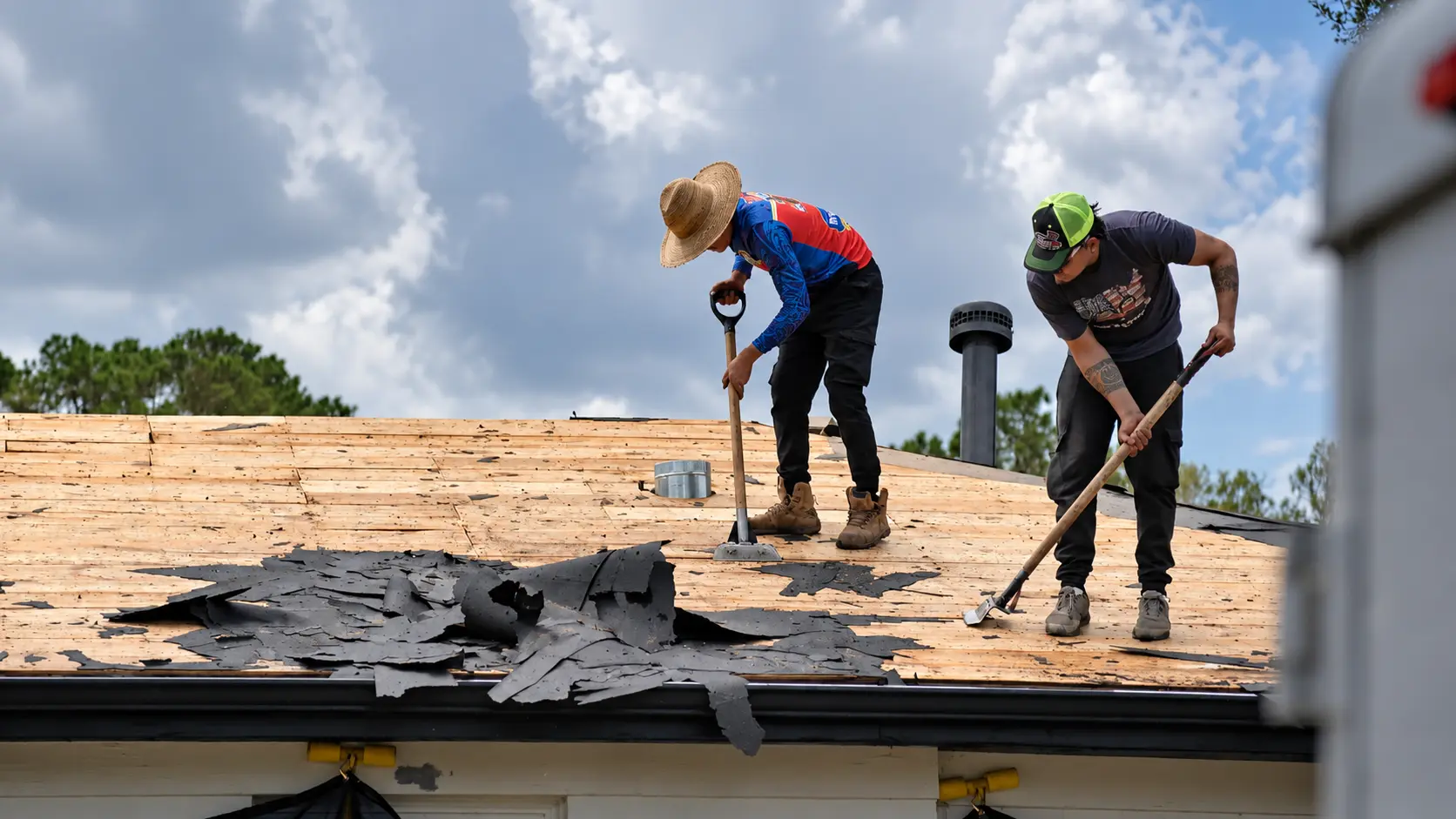 Crew tearing off old shingles down to the roof deck