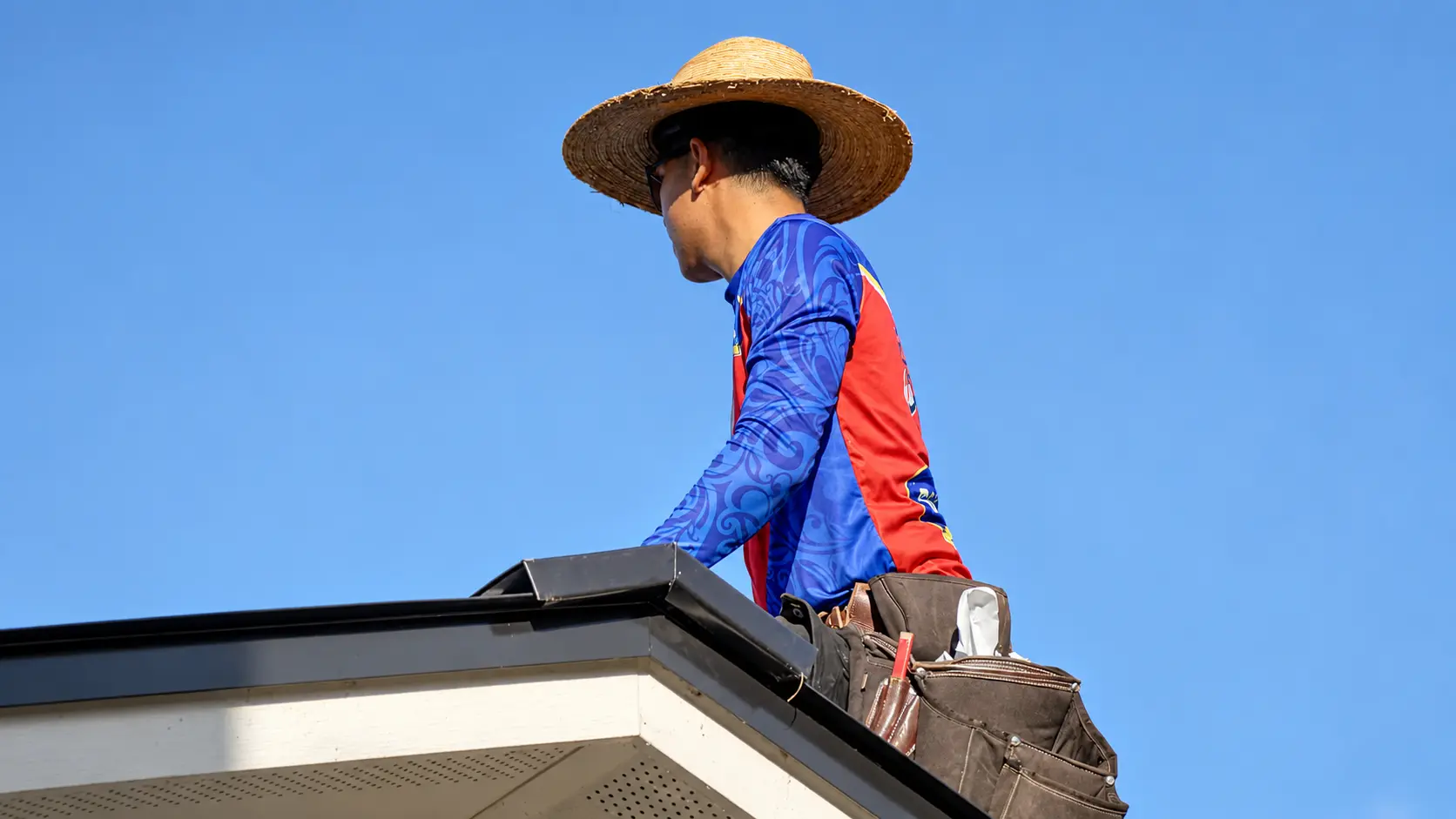Roof Ryders roofer at the roof edge with a tool belt