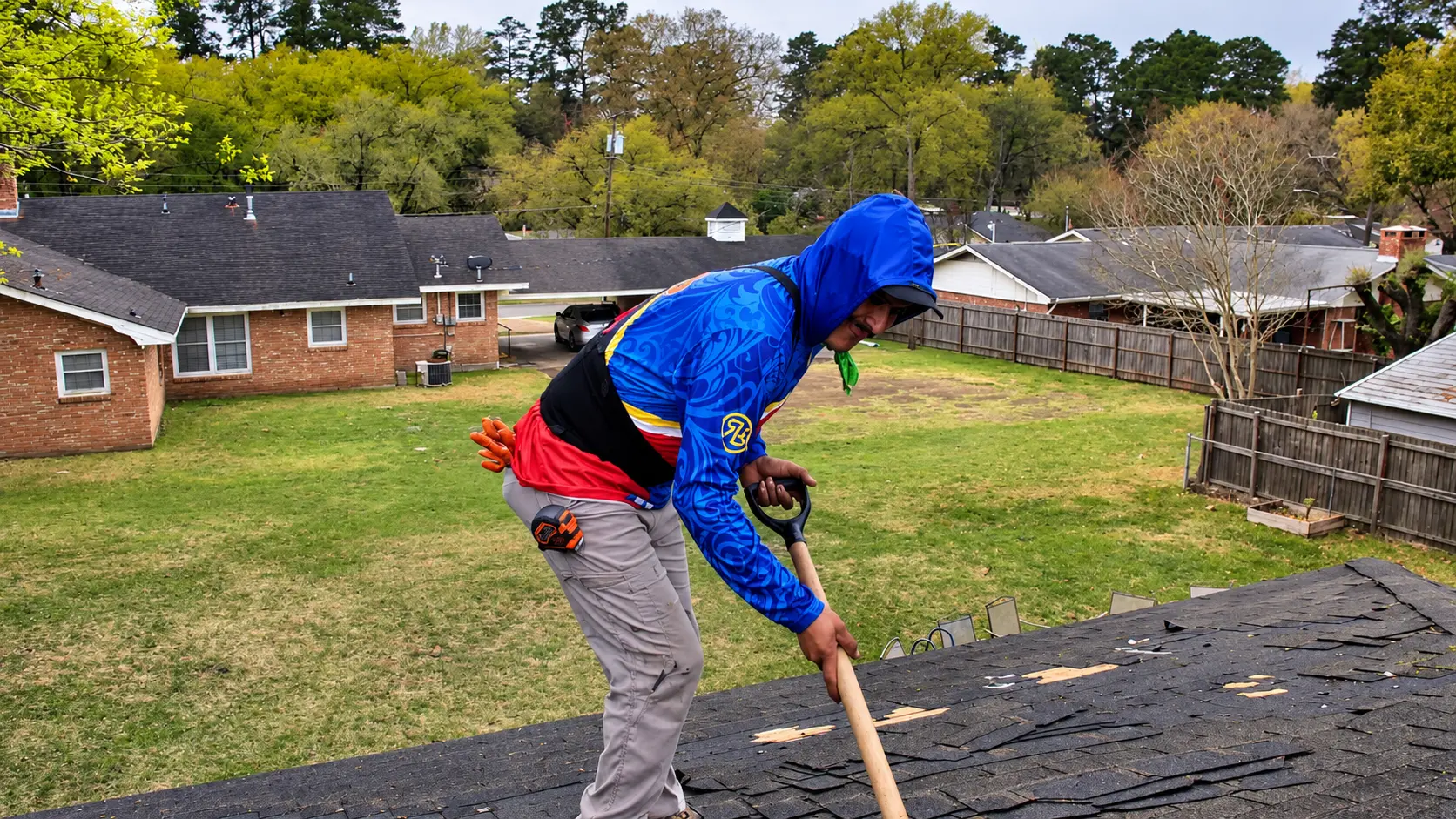 Roofer removing old shingles with a roofing shovel