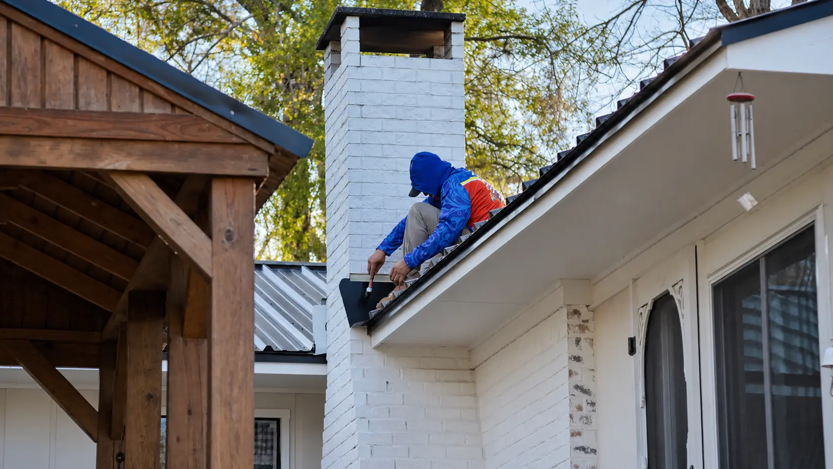 Roofer sealing chimney flashing on a metal roof