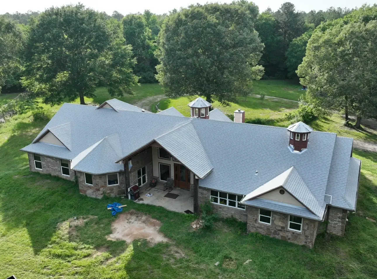 Aerial view of a new shingle roof with cupolas on an East Texas ranch home
