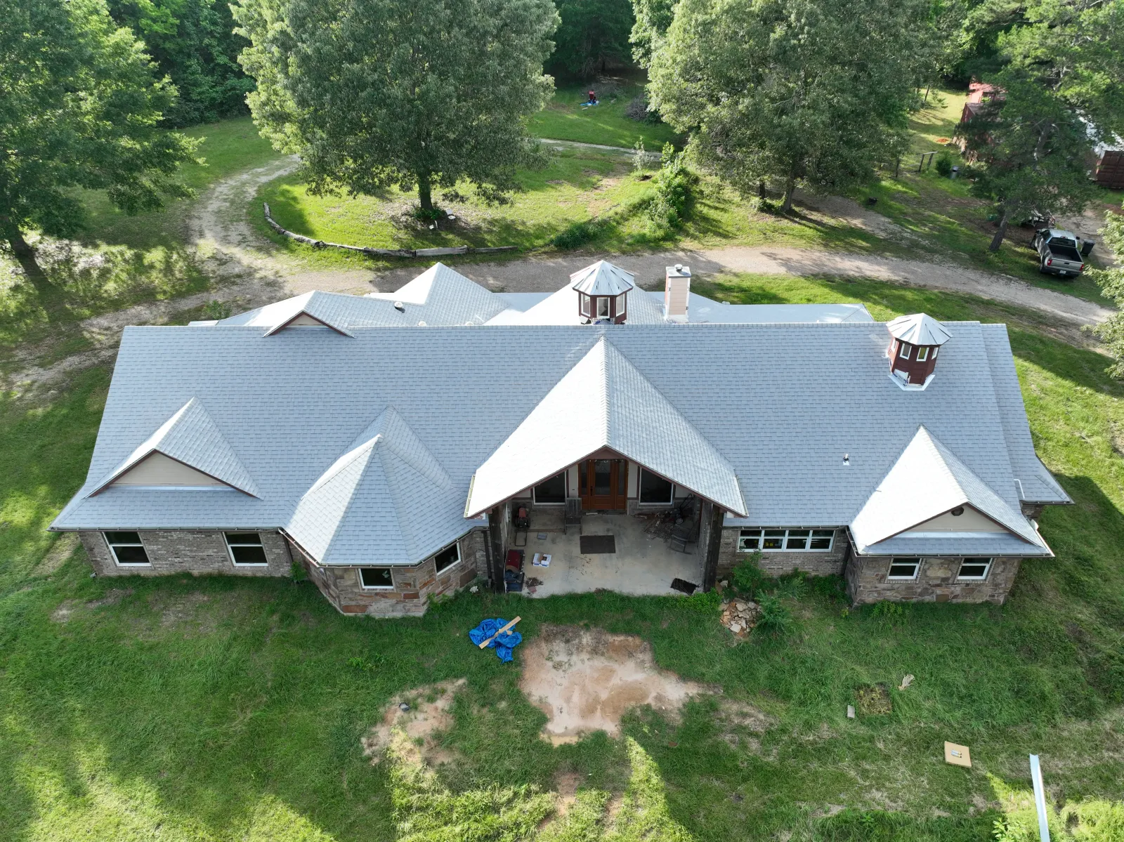 Aerial front view of a shingle roof on a stone ranch home in East Texas